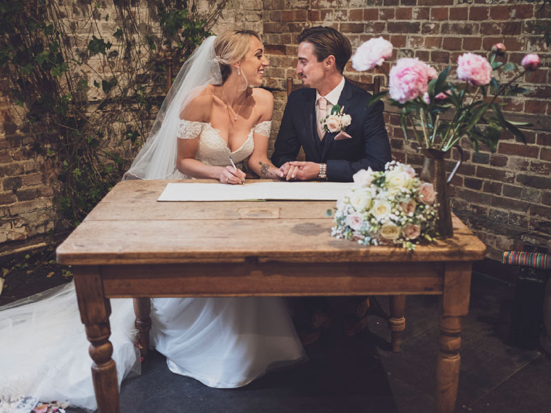 Signing the register at a rustic barn wedding in Hampshire